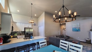 A modern kitchen with white cabinets, a central island, and a dining area with a blue tablecloth.