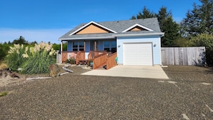 A two-story house with a front porch, a garage, and a gravel driveway.