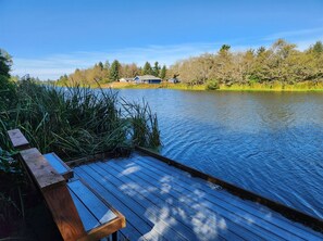 A wooden dock extending into a calm river, surrounded by lush greenery and trees. - Heron Haven - Beautiful newer canal front home (Ocean Shores)