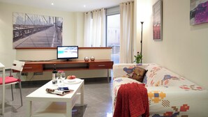A modern living room with a sofa, a dining table, a TV, and artwork on the walls. - BeBarceloner Studios minutes from Pl Universidad (Barcelona)