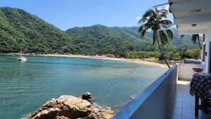 A coastal view with a rocky shoreline, a sandy beach, and a boat in the water. - Velyn (Yelapa)