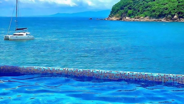 A clear view of a swimming pool with a tiled edge and a sailboat in the background. - Velyn (Yelapa)