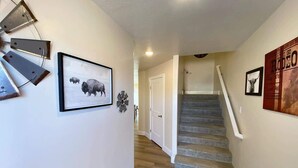 Escada que leva a uma porta, quadro emoldurado de bisões e um objeto decorativo fixado na parede.