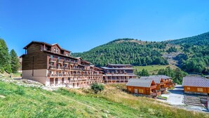 A multi-story hotel with balconies, set in a mountainous area with lush greenery. - Studio 2/4 ppl near the ski runs (Allos)