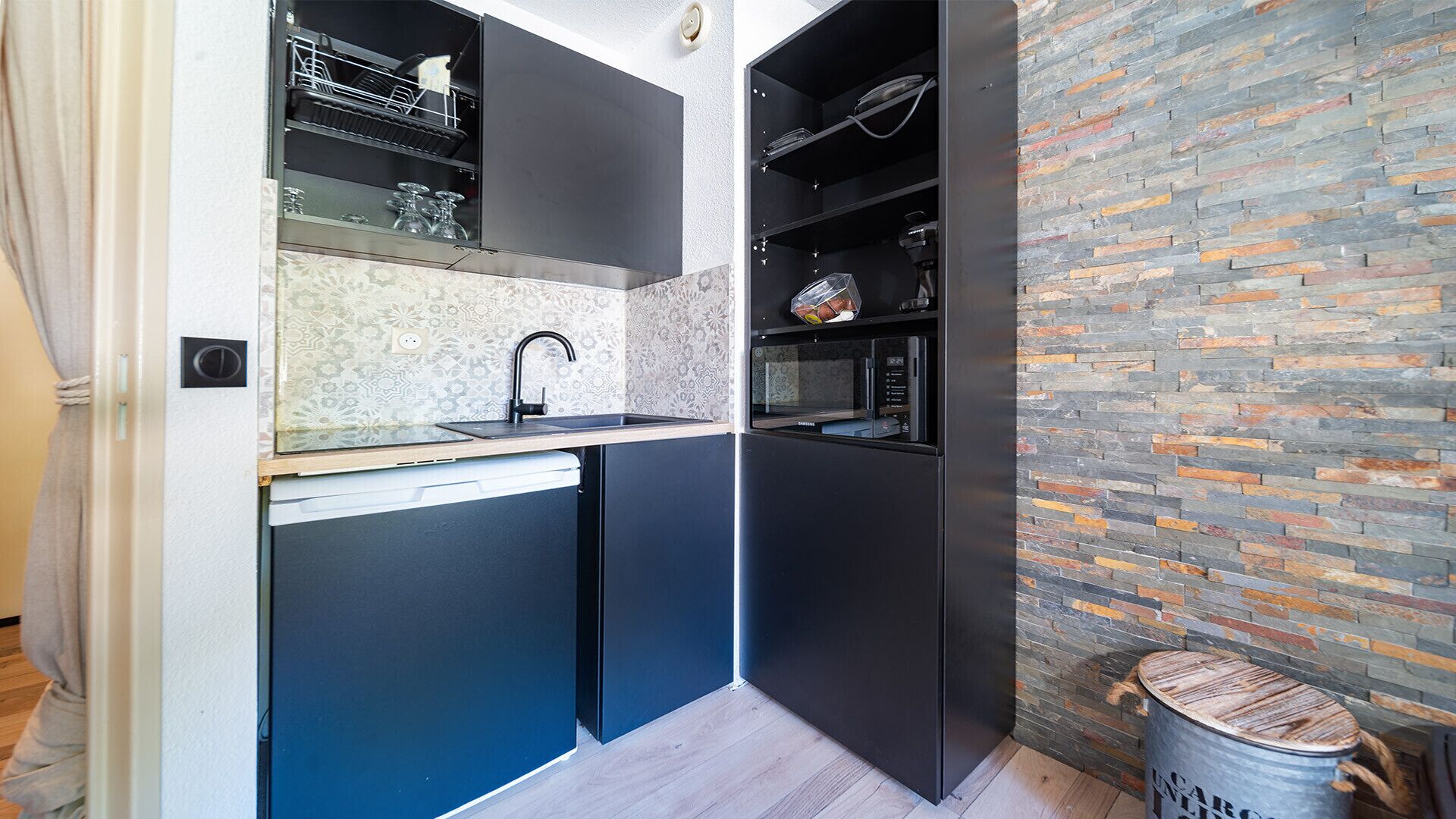 A compact kitchen with a built-in dishwasher, a microwave, and a small sink.