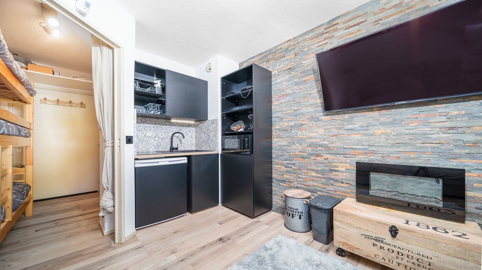A compact kitchen with built-in appliances, a small dining area, and a fireplace.