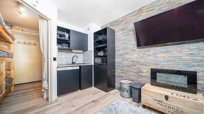 Una cocina compacta con electrodomésticos integrados, un pequeño comedor y una chimenea.