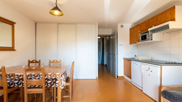 Una cocina compacta con muebles de madera, microondas y lavavajillas.