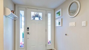 A white door with a frosted glass window, a white wall with a mirror and framed pictures, and a wooden floor. - 🌴2 King Suites, Huge HEATED POOL& SPA, 8 MIN TO OLD TOWN,2 LIVING ROOMS, FIREPIT (Scottsdale)