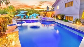 A swimming pool with lounge chairs and umbrellas, surrounded by a house and palm trees. - 🌴2 King Suites, Huge HEATED POOL& SPA, 8 MIN TO OLD TOWN,2 LIVING ROOMS, FIREPIT (Scottsdale)