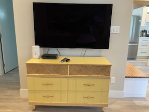 A yellow wooden dresser with drawers and a flat-screen TV mounted above it.