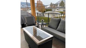A balcony with a glass-top table, two chairs, a sofa, and a small table with a lantern.