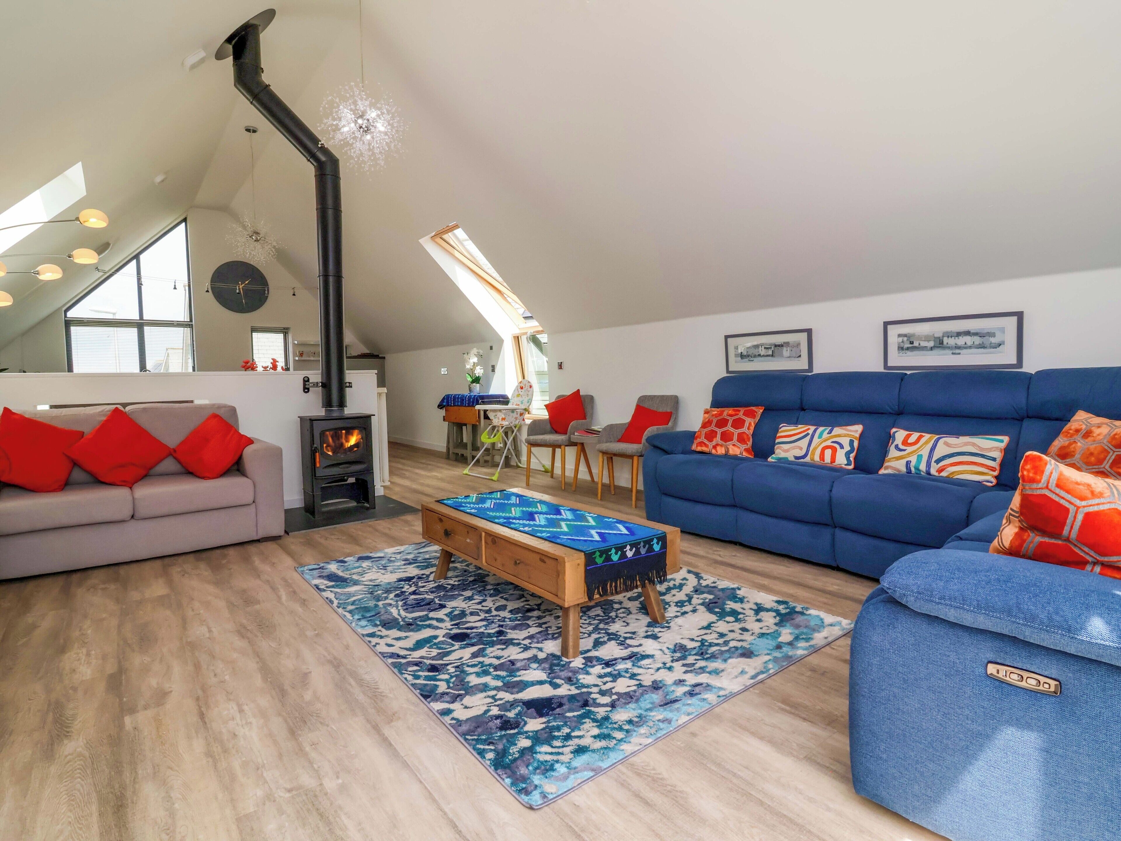 A cozy living room with a sofa, a blue couch, a wooden coffee table, and a fireplace.