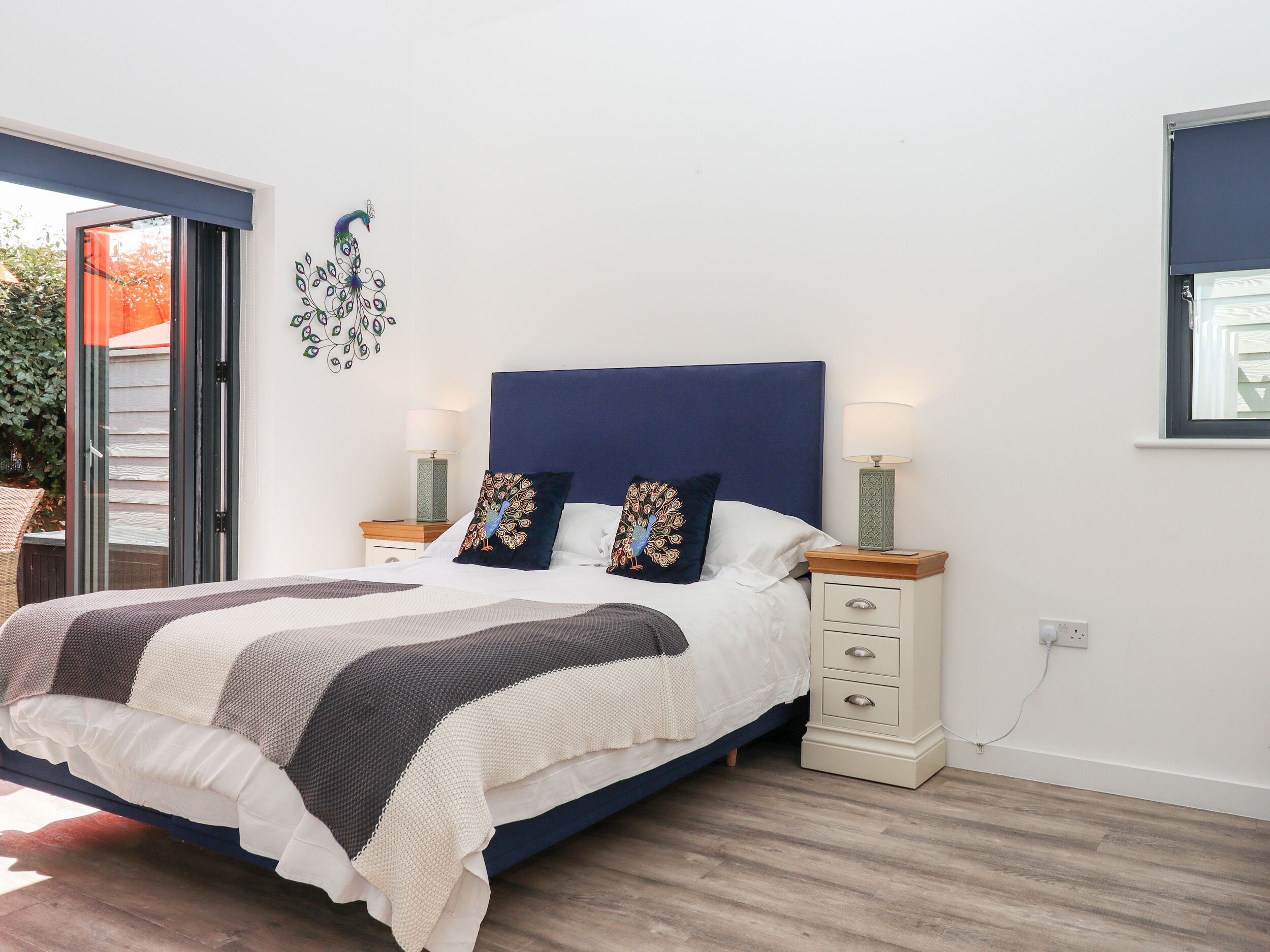 Une chambre à coucher avec un lit, deux tables de chevet, une fenêtre et une porte.