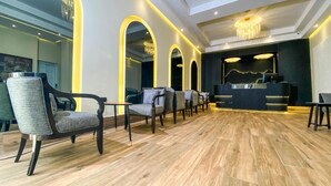 A modern hotel lobby with wooden flooring, a reception desk, and several seating areas. - Ennasma (Casablanca)
