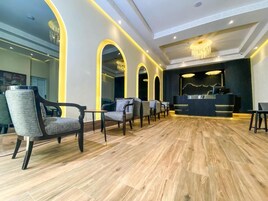 Un moderno vestíbulo de hotel con suelo de madera, un mostrador de recepción y varias zonas de estar.
