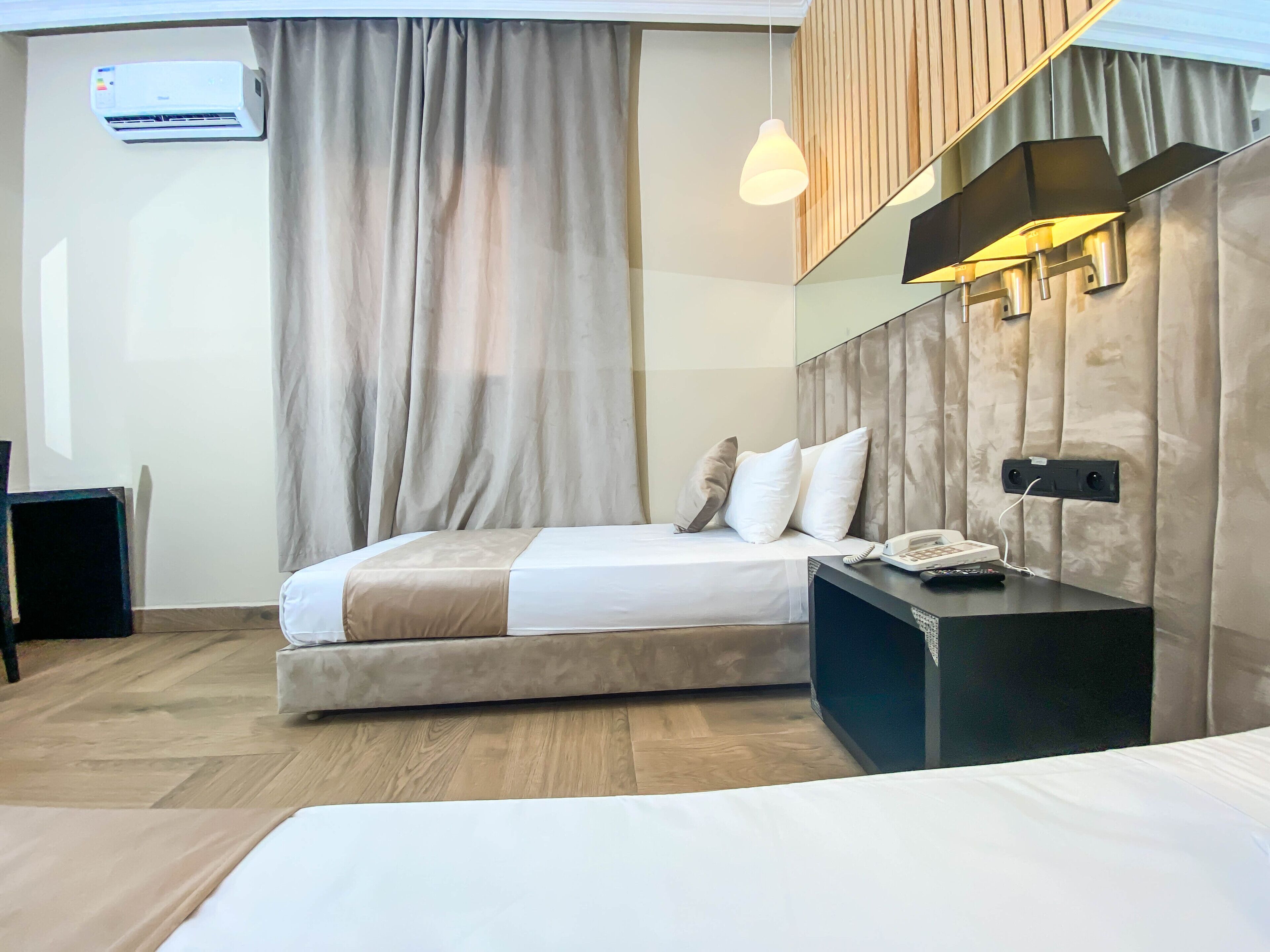 Une chambre d’hôtel moderne équipée d’un lit, d’une table de chevet et d’un appareil de climatisation.