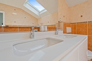 A modern bathroom with two sinks, a skylight, and a large mirror. - Spacious House in Kehlen ID182 (Kehlen)