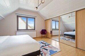 A bedroom with a bed, a window, a chair, and a mirror. - Spacious House in Kehlen ID182 (Kehlen)
