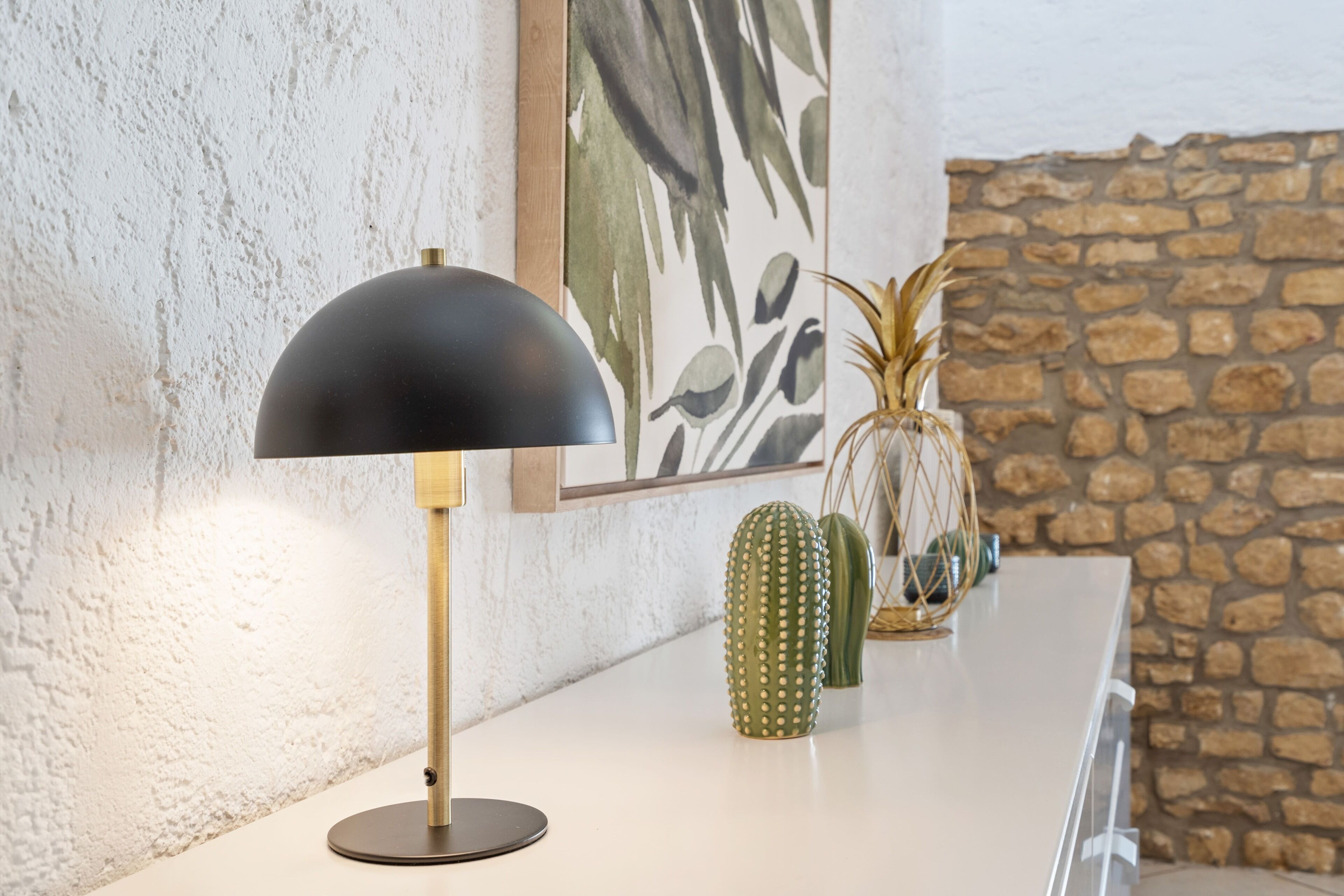 Ein modernes Interieur mit einem runden Tisch, einer schwarzen Lampe und dekorativen Pflanzen.