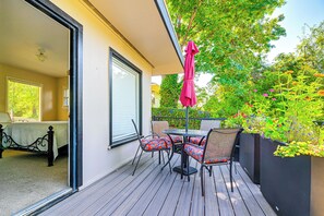 Enjoy a peaceful retreat on this balcony with a table and chairs, overlooking a serene garden.