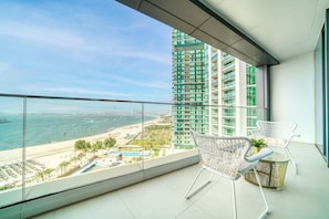 Un balcon avec vue sur une plage et un immeuble de grande hauteur.