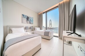 A hotel room with two beds, a desk, a TV, and a large window with a view of a Ferris wheel. - Modern 2BR w/ Sea View Balcony at Address JBR (Dubai)