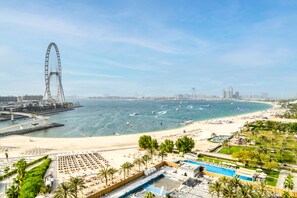 Un resort frente al mar con una noria gigante, una piscina y una playa de arena.