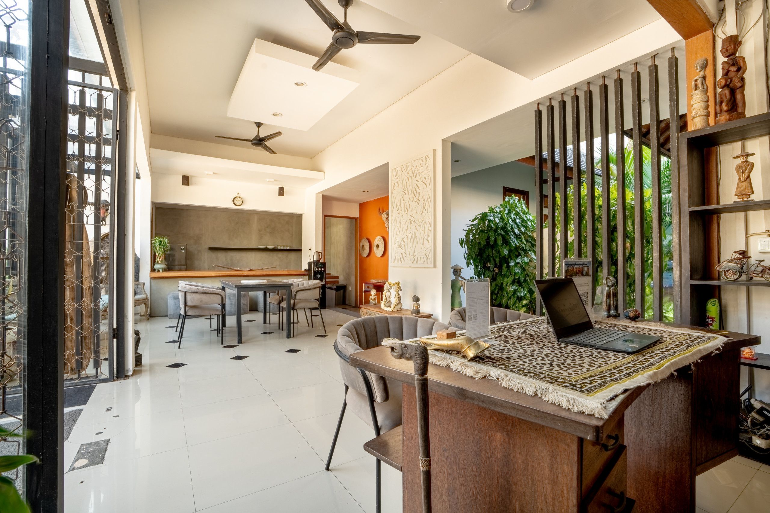 Una cocina moderna con comedor, una computadora portátil sobre una mesa y una planta grande.