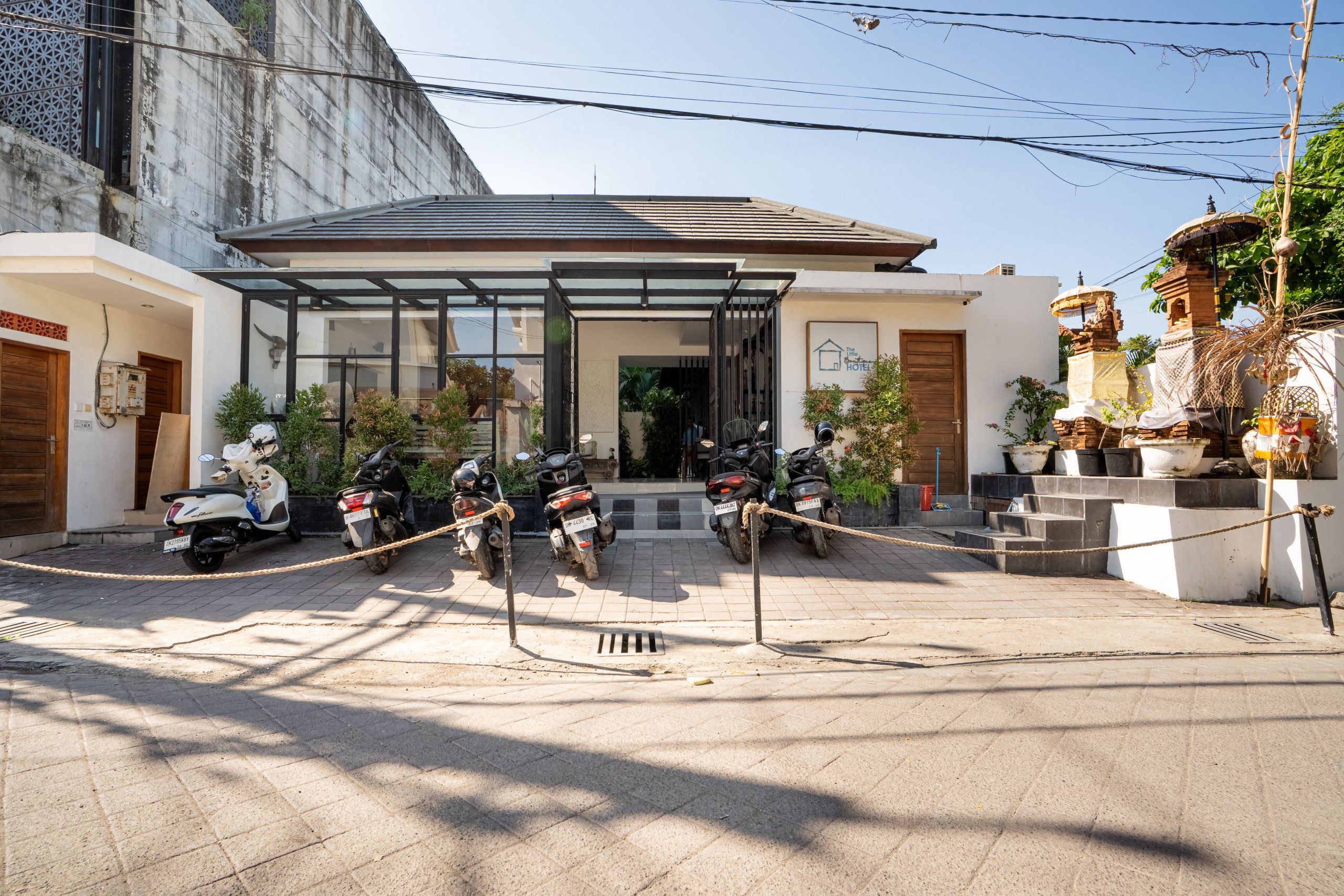 A hotel entrance with a covered walkway, parked motorcycles, and a traditional decorative structure.
