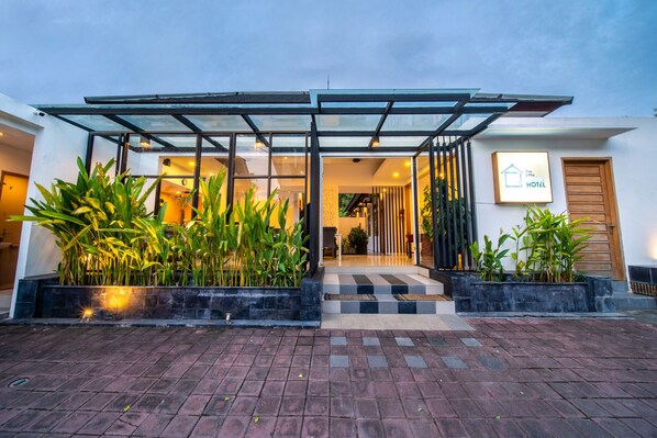 A modern hotel entrance with a glass canopy, potted plants, and a checkered pathway leading to the door. - Seaside Boutique Hotel 108 (30m from beach) (Canggu)