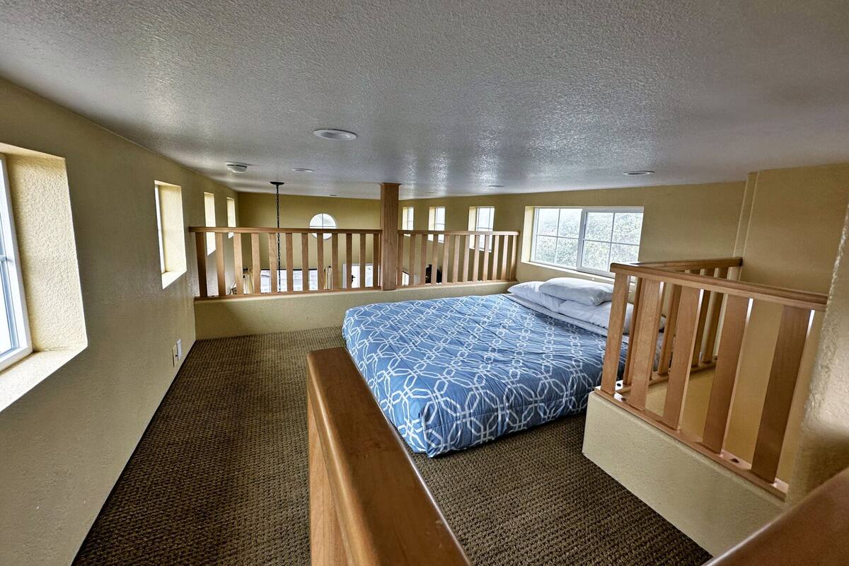 A bedroom with a bunk bed, wooden railings, a window, and a ceiling fan.