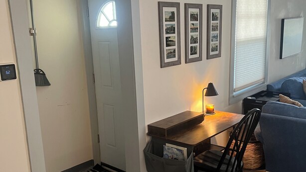 Un salon moderne avec un plancher en bois, un canapé bleu, une table à manger avec une chaise et une lampe fixée au mur.