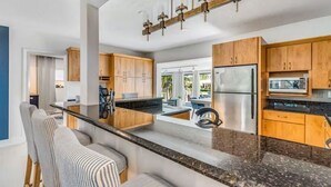 A modern kitchen with wooden cabinets, a granite countertop, and a stainless steel refrigerator.