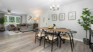 Ein modernes Wohnzimmer mit Esstisch, Stühlen, einer Couch und einer Kandelaber.