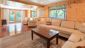 A spacious living room with a large sofa, two armchairs, and a wooden coffee table.