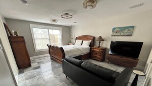 Ein Schlafzimmer mit Bett, Fernseher, Sofa und Kommode.
