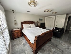 Ein Schlafzimmer mit einem hölzernen Bett, einem Nachttisch, einer Kommode, einem Fernseher und einem Kleiderschrank.