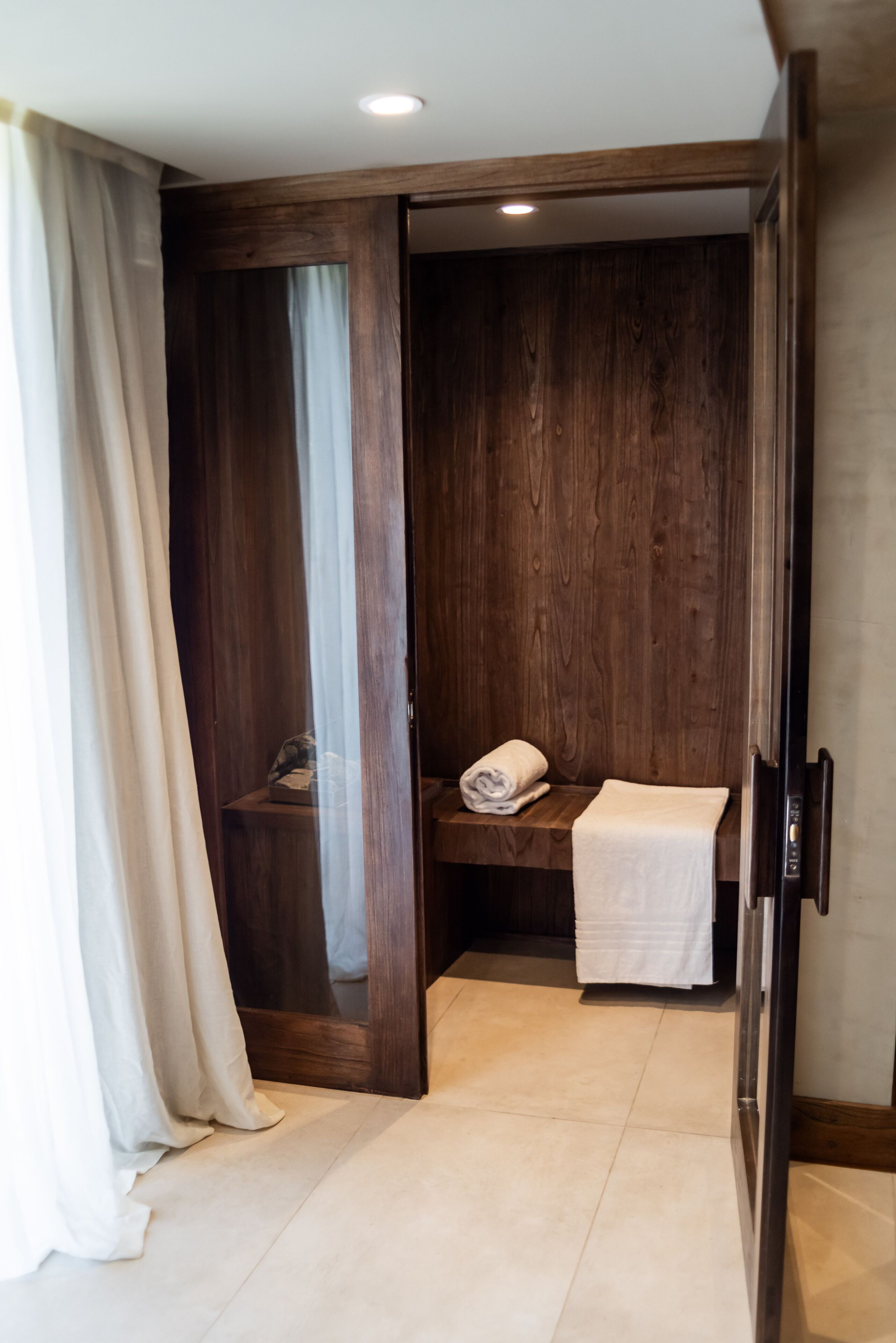 Un vestidor de madera con un banco y una toalla.