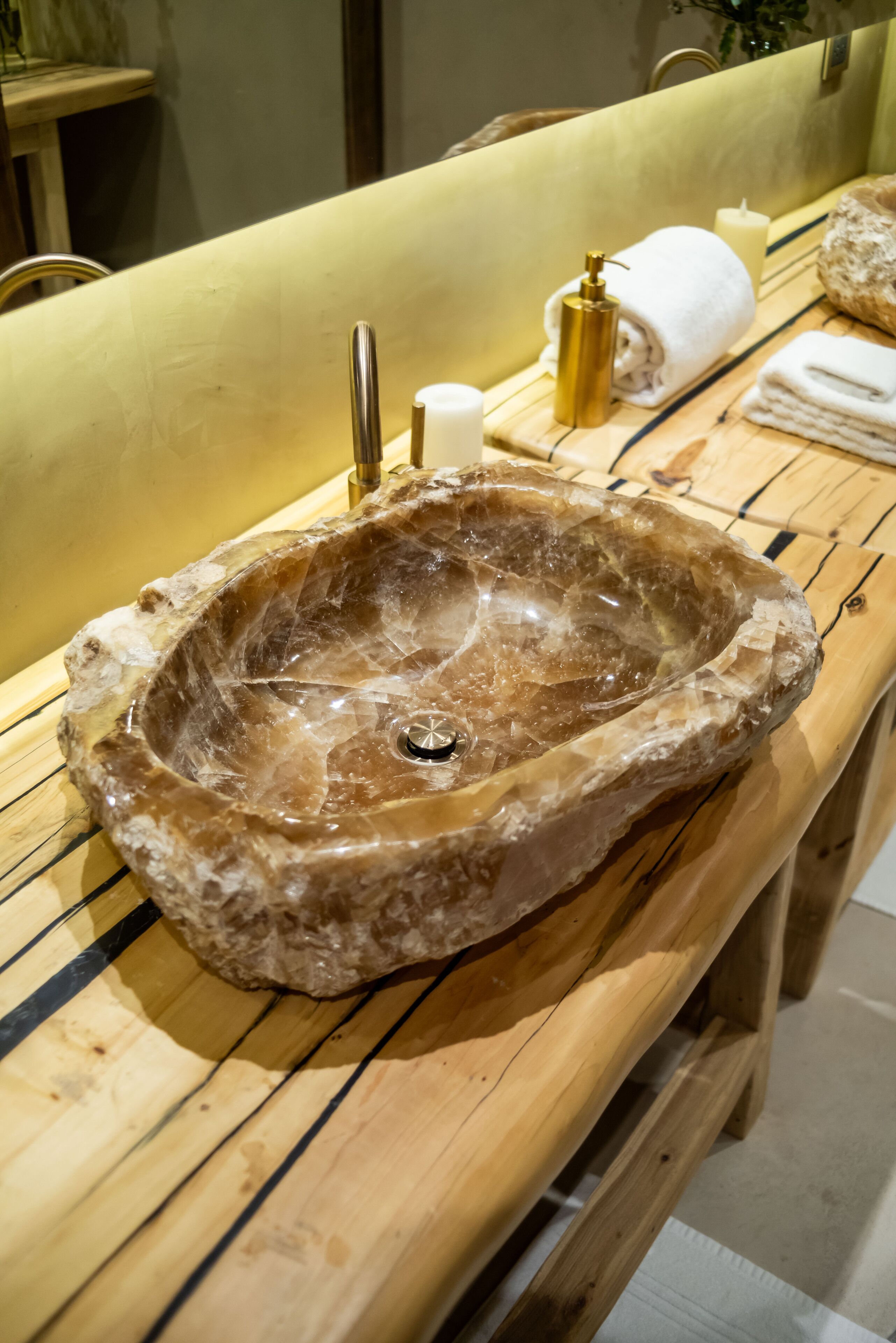 A bathroom with a large, natural stone sink, wooden vanity, and a mirror.