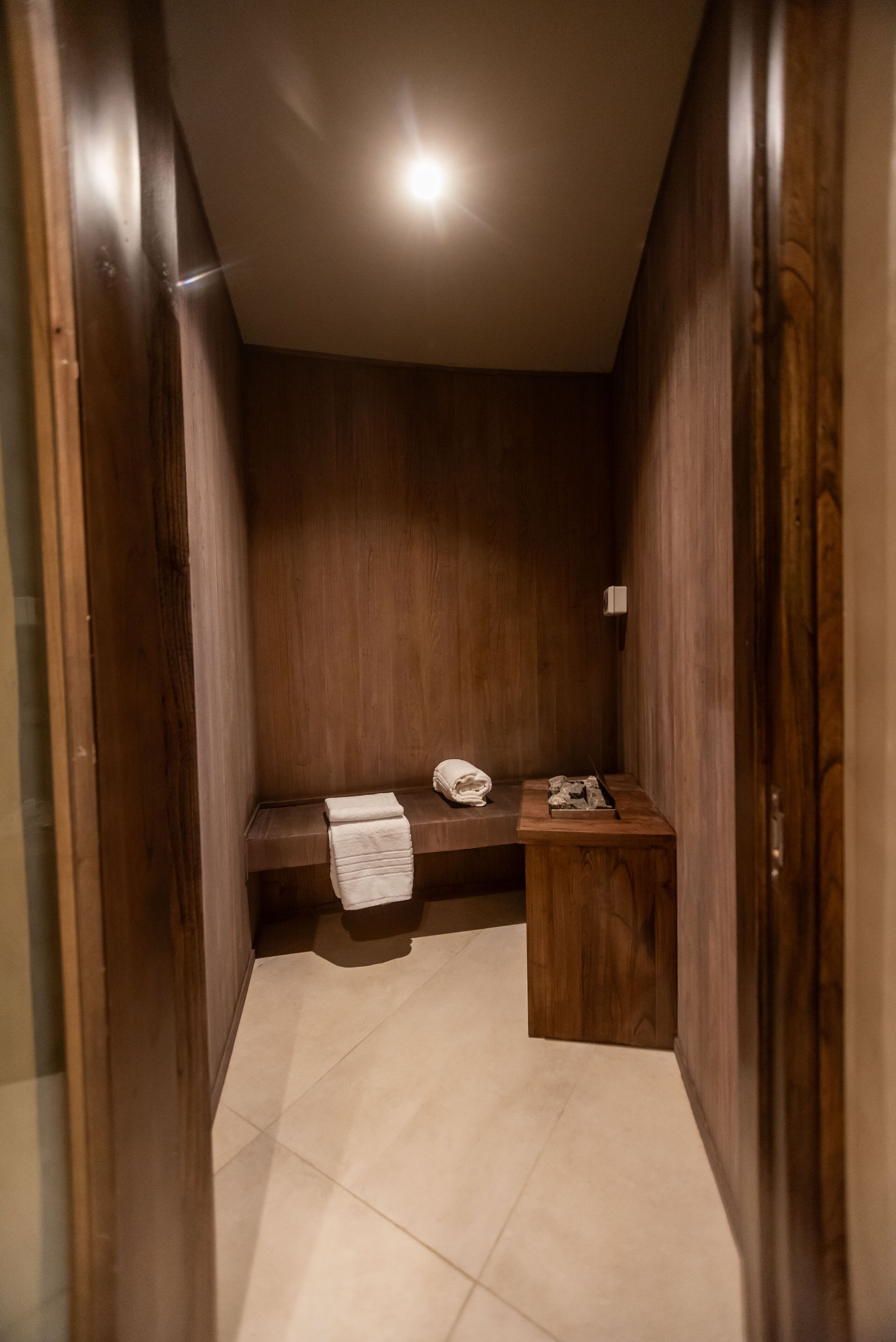 Un baño pequeño y cerrado con paredes de madera y un banco.