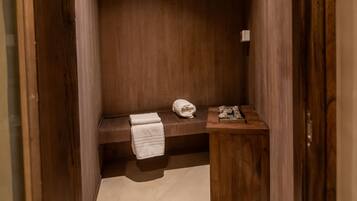 Un baño pequeño y cerrado con paredes de madera y un banco.
