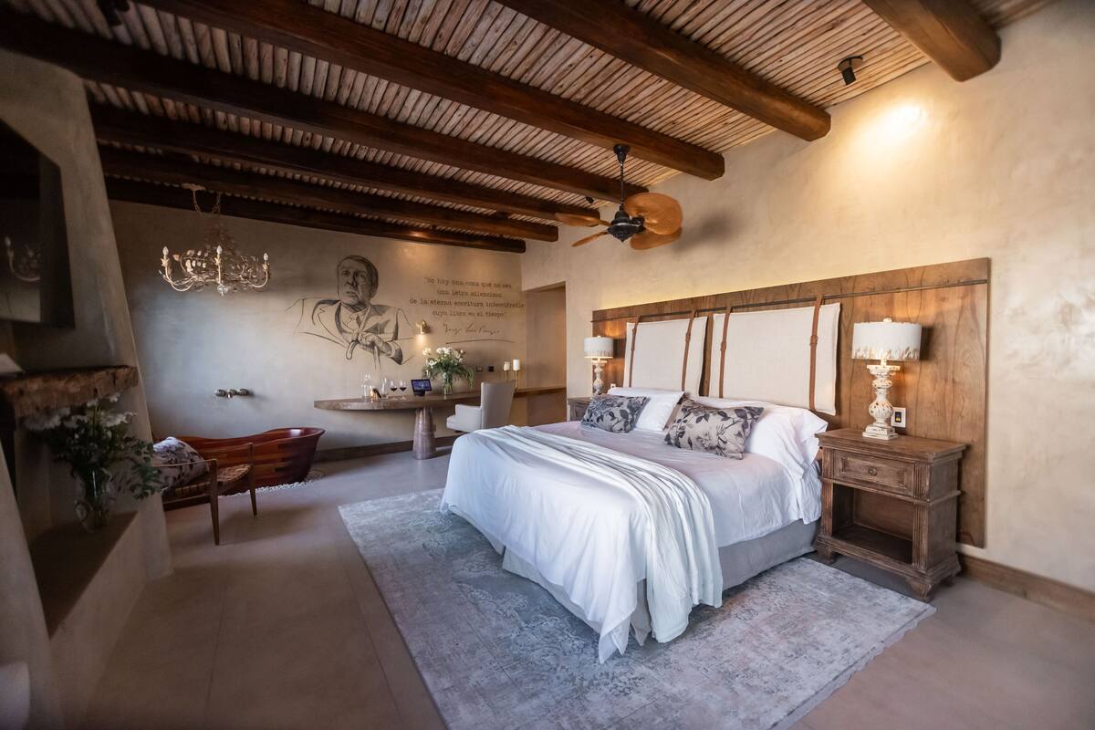 A bedroom with a large bed, wooden headboard, and a ceiling fan.