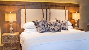 A neatly made bed with floral pillows, a wooden headboard, and two bedside lamps on matching nightstands.