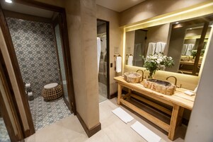 Un baño con tocador de madera, un espejo grande y un papel tapiz decorativo.
