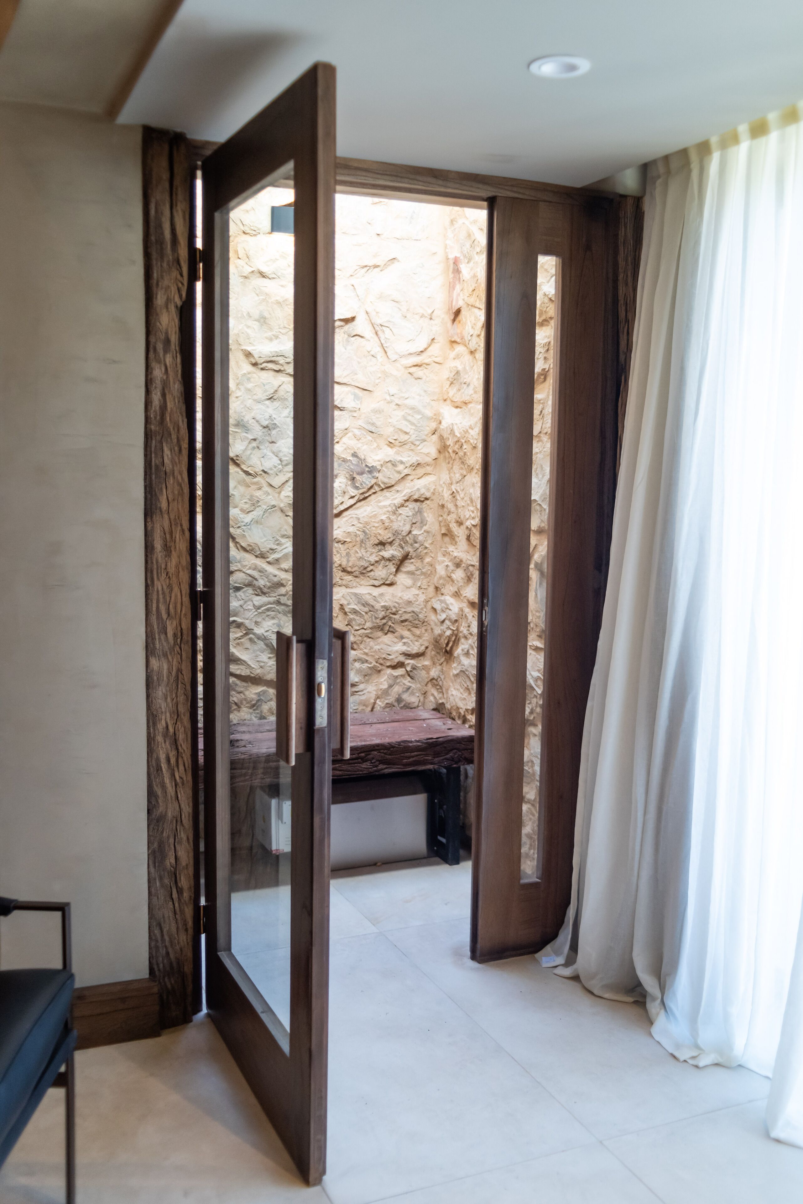 Una habitación con un amplio ventanal corredera que da a un muro de piedra.