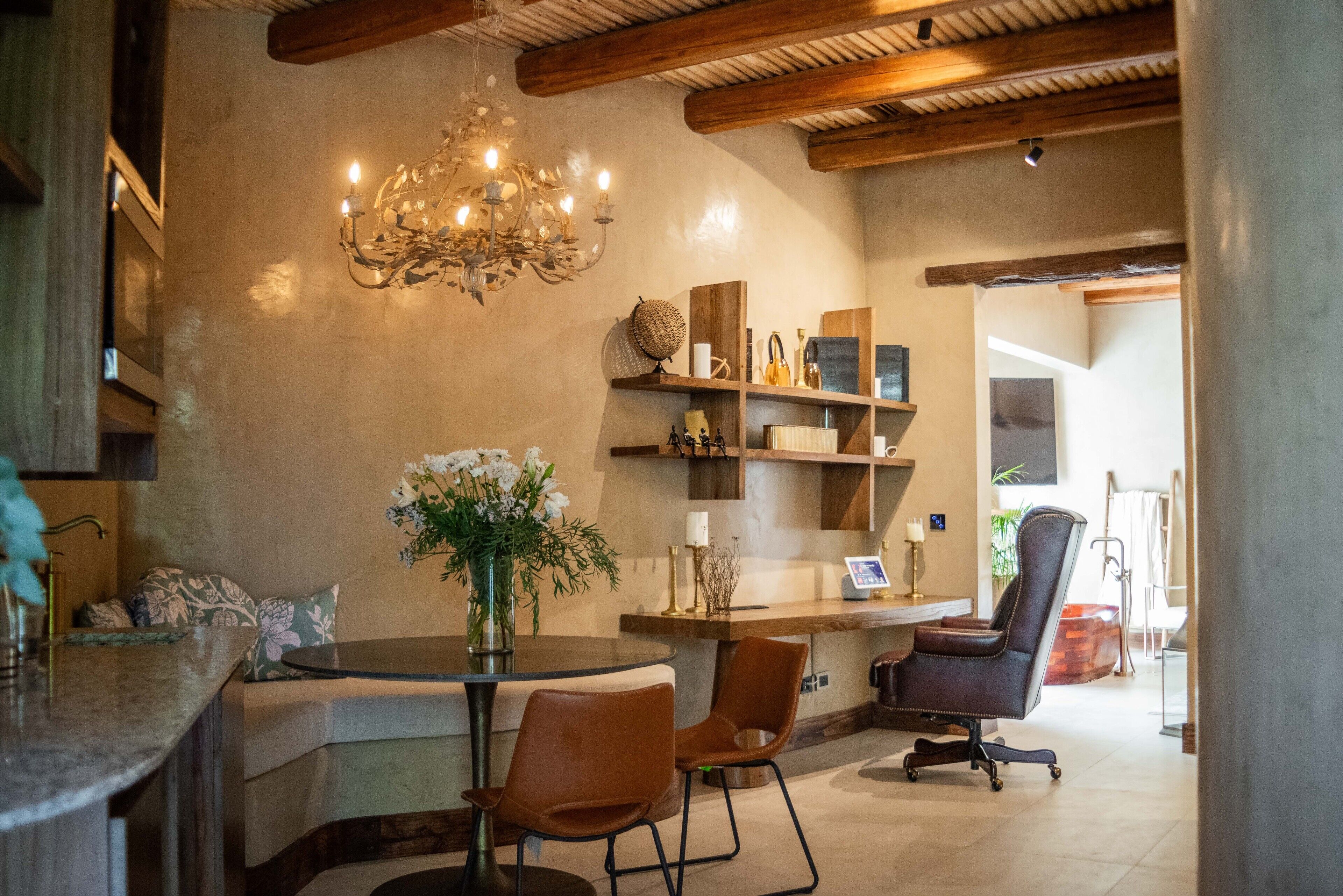 Un intérieur moderne avec une table de salle à manger ronde, deux chaises, un lustre et un plafond en bois.