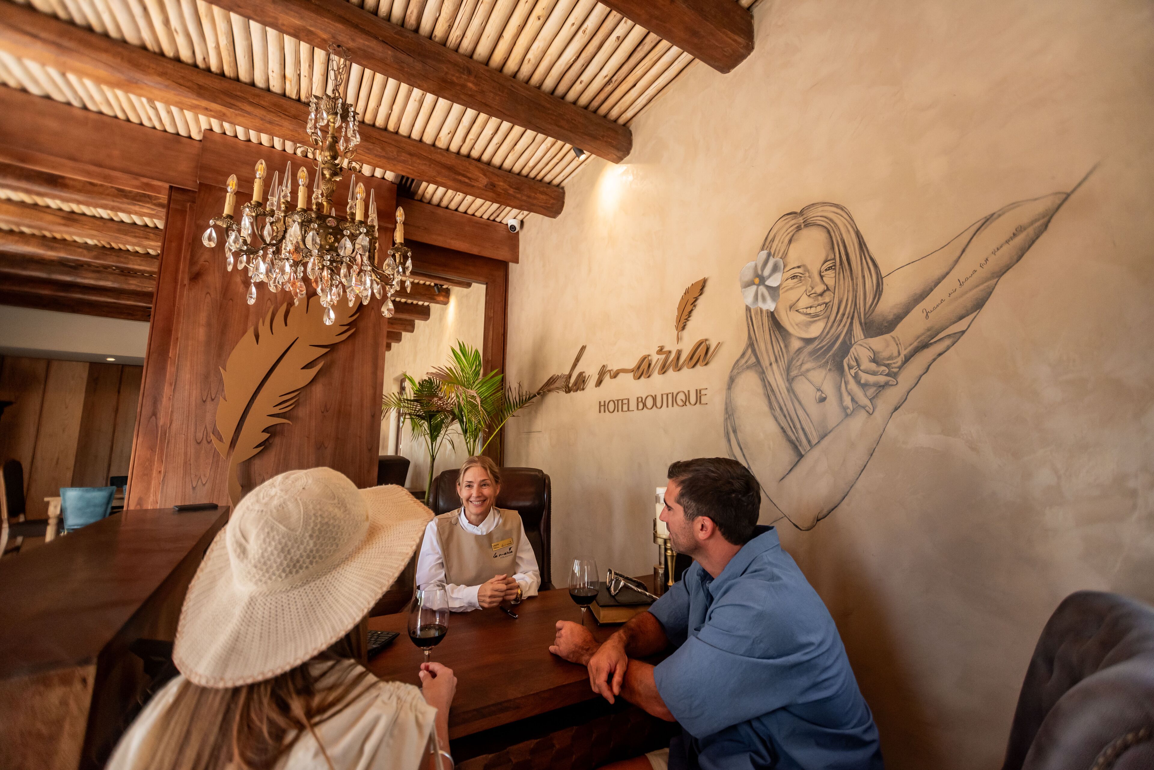 Un interior de madera con un candelabro, un mural en la pared y una mesa con personas sentadas.