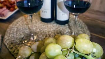 A table with two wine bottles, two wine glasses, and a plate of grapes.