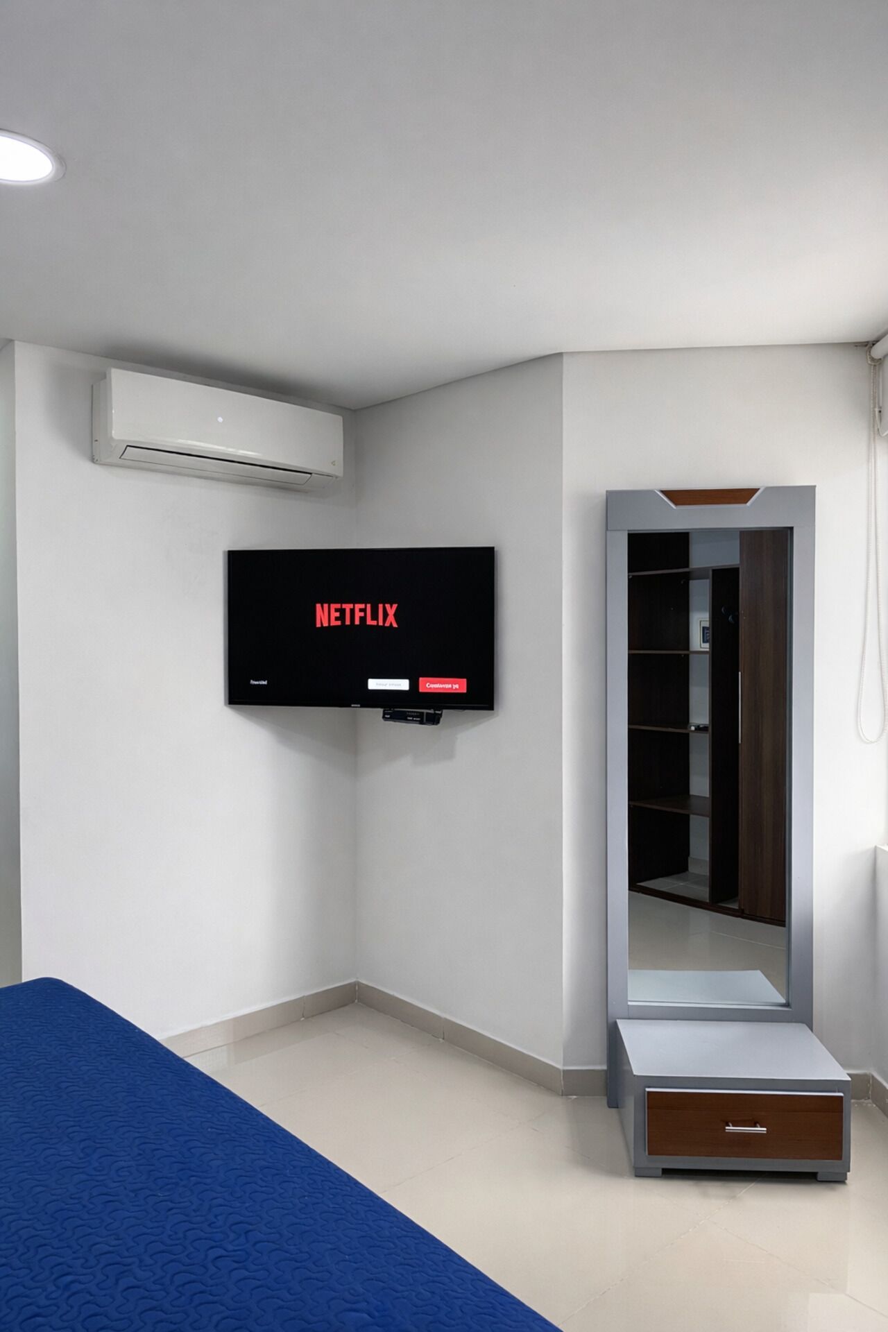 A room with a flat-screen TV mounted on the wall, a wardrobe with a mirror, and a small step for access.
